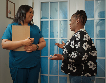 Two People Standing and Talking, With One Person Holding a Clipboard