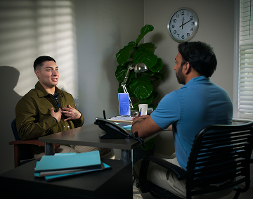 Two People Talking Across a Desk in an Office