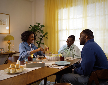 Three People Sit at a Dining Table Together